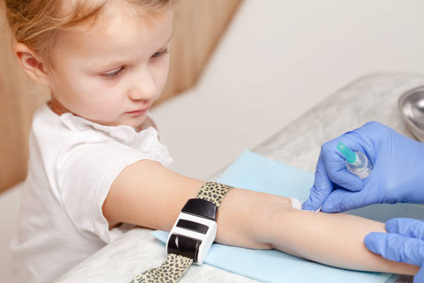 Nurse disinfects arm of little girl before performing a venipuncture stock photo