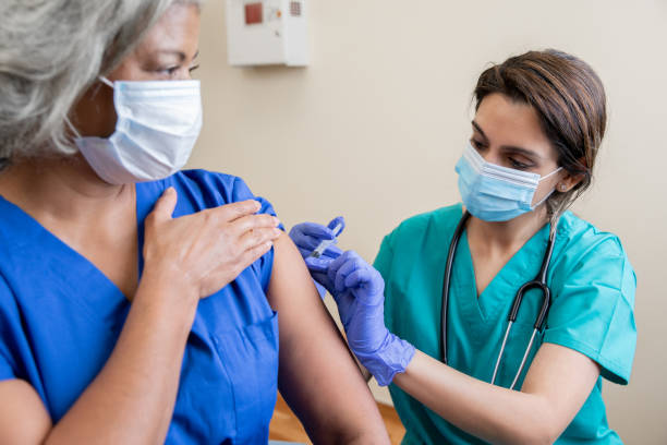de verpleegster geeft hogere volwassen gezondheidszorgarbeider het vaccin covid-19 - vaccinatie stockfoto's en -beelden