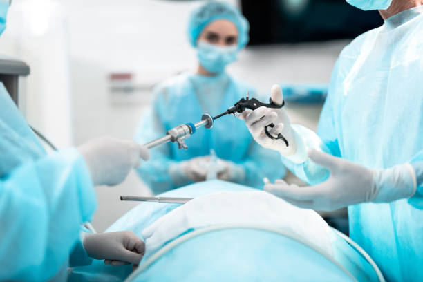 Nurse giving laparoscopic instrument to doctor during surgical operation stock photo