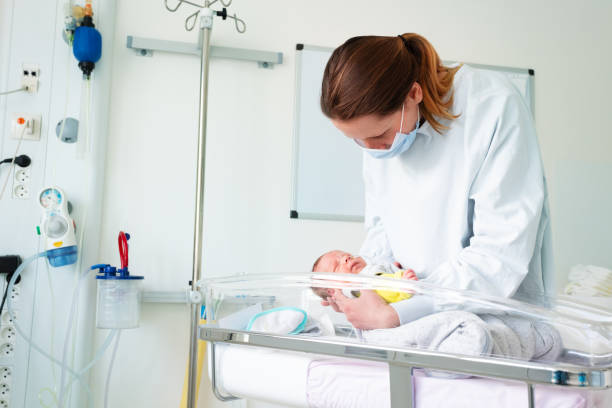 Nurse in ICU examining premature born infant Female nurse with premature born baby in intensive care unit holding infant in her hands midwife stock pictures, royalty-free photos & images