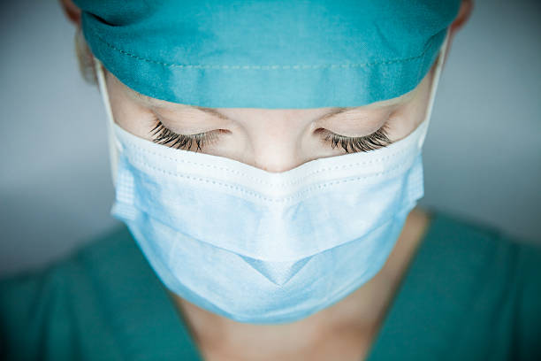 enfermera mirando hacia abajo - nurse face fotografías e imágenes de stock