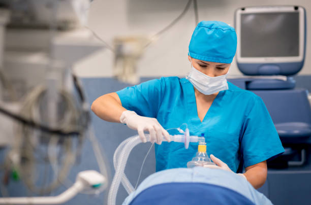Nurse putting oxygen mask to patient during surgery Nurse putting oxygen mask to patient during surgery - healthcare and medicine concepts anesthetic stock pictures, royalty-free photos & images