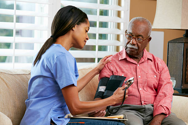 Nurse Visiting Senior Male Patient At Home Nurse Visiting Senior Male Patient At Home Taking Blood Pressure blood pressure gauge stock pictures, royalty-free photos & images