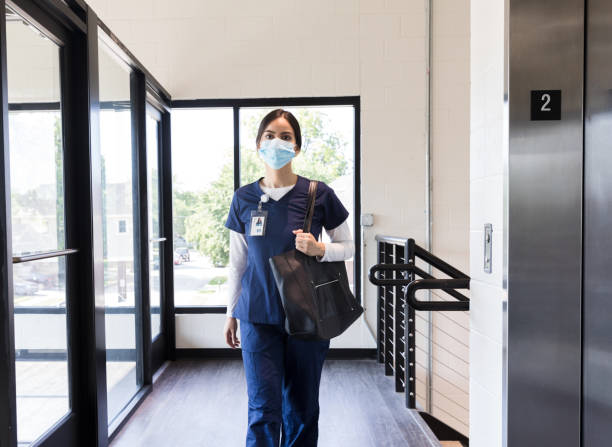 Nurse wearing mask because of coronavirus epidemic arrives at work Female nurse arrives for work at medical clinic wearing a protective mask for coronavirus pandemic. worker returning home stock pictures, royalty-free photos & images