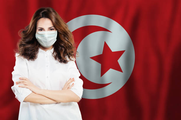Nurse with face mask against national flag Tunisia. Flu epidemic and virus protection concept Nurse with face mask against national flag Tunisia. Flu epidemic and virus protection concept tunisia woman stock pictures, royalty-free photos & images