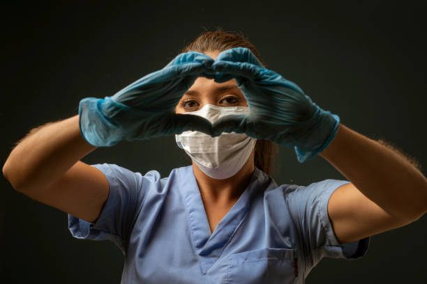 Nurse with gloves and mask thanking ereyone and making hearts Nurse with gloves and mask thanking ereyone and making hearts coronavirus female nurse stock pictures, royalty-free photos & images