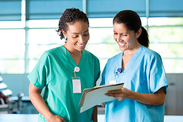 Nurses or physical therapists discuss patient Diverse nurses and physical therapists discuss a patient's progress. They are looking at the patient's medical chart. They smile as discuss the patient. nail file stock pictures, royalty-free photos & images