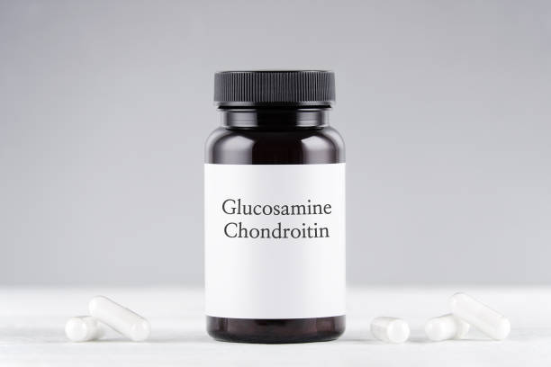 nutritional supplement glucosamine and chondroitin bottle and capsules on gray nutritional supplement glucosamine and chondroitin bottle and capsules on gray background glucosamine stock pictures, royalty-free photos & images