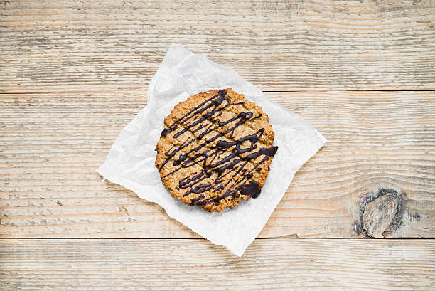 Oatmeal cookie topped with chocolate on wooden table. Top view stock photo