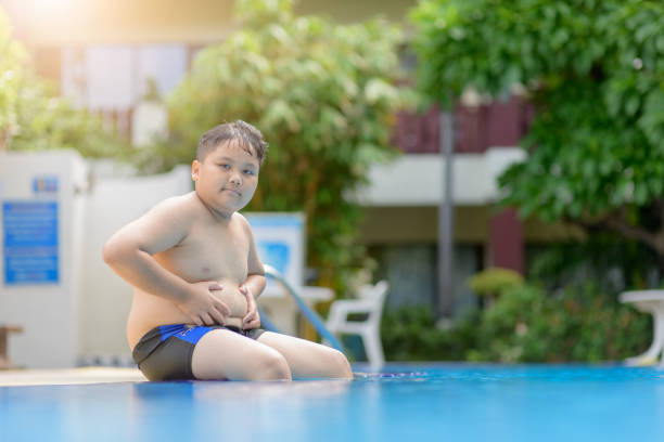 obese fat boy sit on swimming pool - heavy pool стоковые фото и изображения...