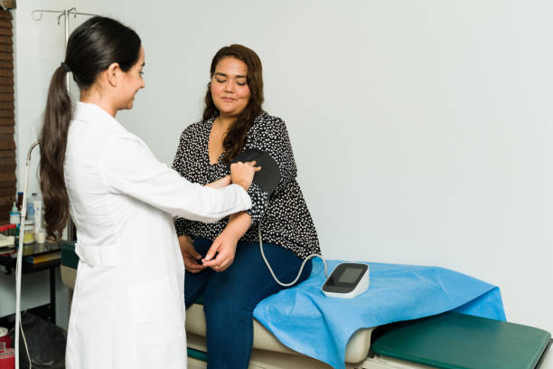 Obese woman getting a check-up Happy female cardiologist checking the blood pressure of a sick female patient for a medical examination obesity stock pictures, royalty-free photos & images