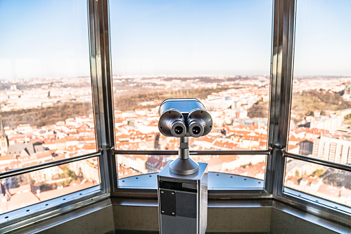 Observation telescope in Prague against window with panorama