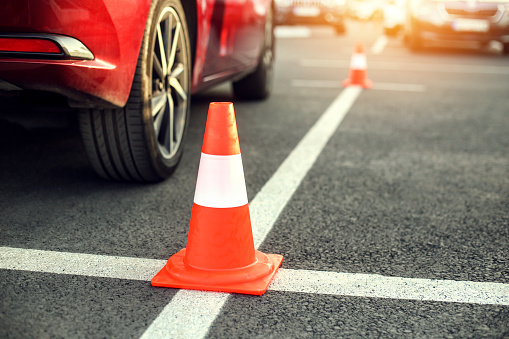 Driving obstacle course - asphalt, traffic cone and a car.
