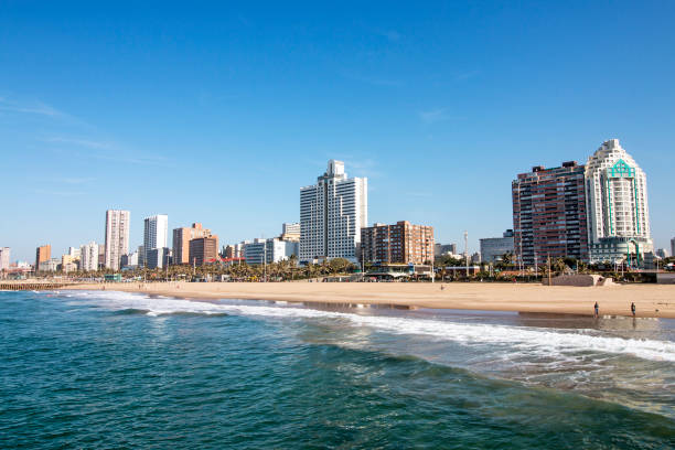 Ocean and Beach Against City Skyline Durban South Africa Ocean and beach against Golden Mile coastal city skyline and blue sky in Durban, South Africa durban stock pictures, royalty-free photos & images