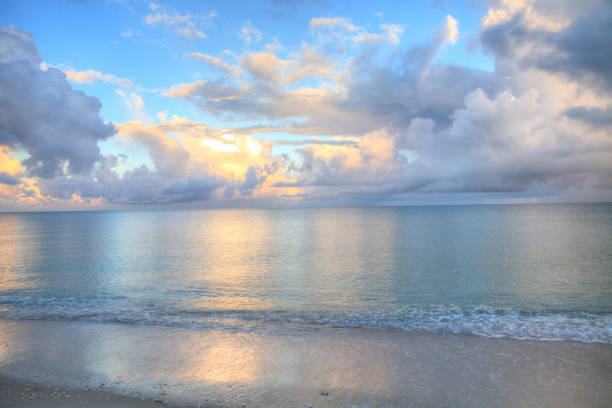 Ocean rolls in under puffy clouds on North Naples Beach Ocean rolls in under puffy clouds on North Naples Beach at sunrise in Naples, Florida naples florida beach stock pictures, royalty-free photos & images