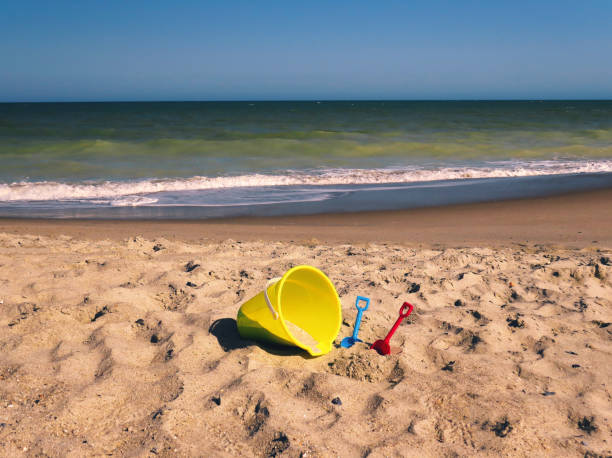 Ocean Sand Pail Sunset A warm landscape of a child's sand pail and shovels on an ocean beach with an emerald ocean in the background at sunset. carolina beach north carolina stock pictures, royalty-free photos & images