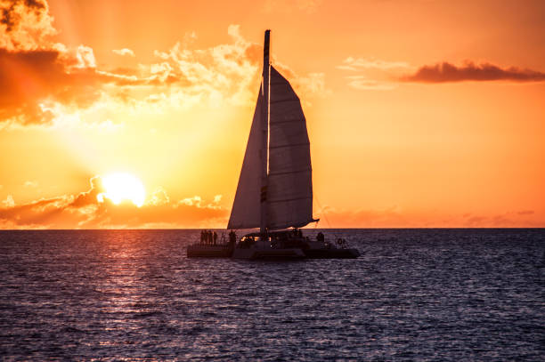 Ocean sunset sailboat silhouette with a bright sun stock photo