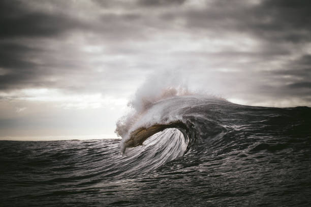 Ocean wave forming in front of dark grey skies stock photo