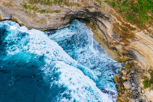 Bali, aerial shot of the blue ocean and beach full of big rocks.