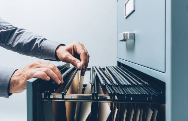 Office clerk searching for files Office clerk searching for files into a filing cabinet drawer close up, business administration and data storage concept file folder stock pictures, royalty-free photos & images