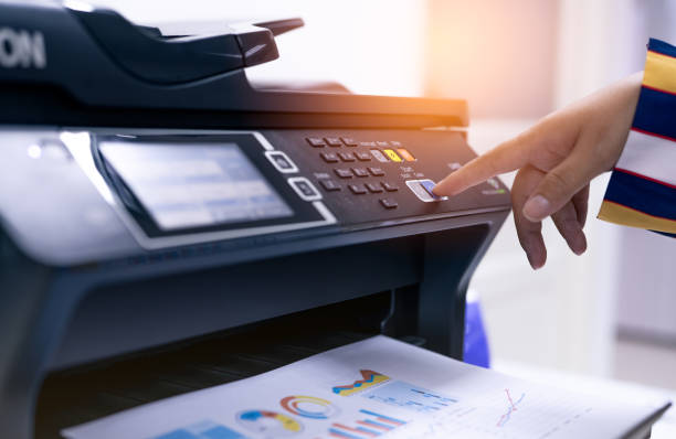 Office worker print paper on multifunction laser printer. Copy, print, scan, and fax machine in office. Modern print technology.  Photocopy machine. Document and paper work. Professional scanner. stock photo