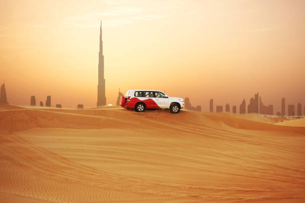Off-road adventure with SUV in Arabian Desert at sunset with Dubai skyline or cityscape stock photo