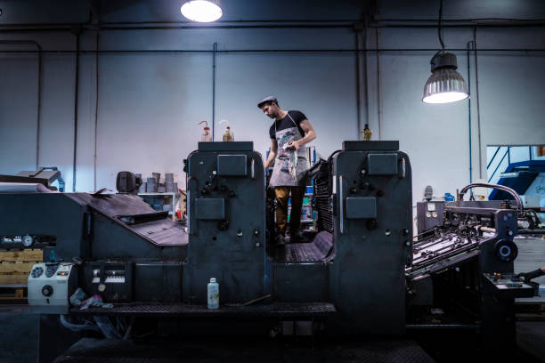 Offset printer man with 2 colors printer Offset printer man with 2 colors printer working in printing industry printing press stock pictures, royalty-free photos & images