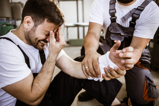Oh my God, my arm hurts so much! Painful manual worker injured his hand at workshop while his colleague is helping him. physical injury stock pictures, royalty-free photos & images