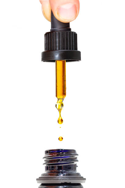 CBD Oil Dropper Closeup photo of person dispensing drops of healthy herbal medicinal marijuana CBD oil cbd oil stock pictures, royalty-free photos & images
