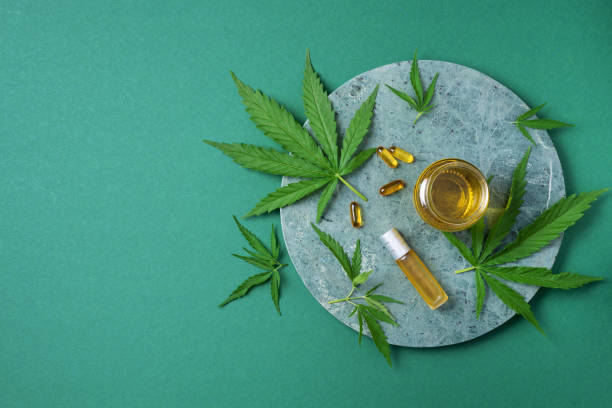 CBD oil, hemp oil capsules and cannabis leaves on green background. Flat lay, copy space. Cosmetics CBD oil. Alternative medicine. Natural supplements, treatment CBD oil, hemp oil capsules and cannabis leaves on green background. Flat lay, copy space. Cosmetics CBD oil. Alternative medicine. Natural supplements, treatment. cbd oil stock pictures, royalty-free photos & images