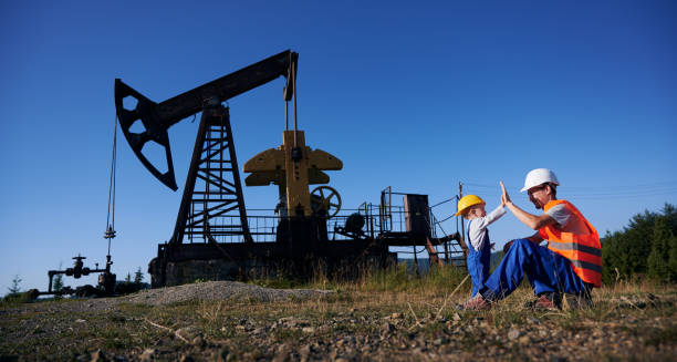 Oil man and little boy giving high five in oil field. stock photo