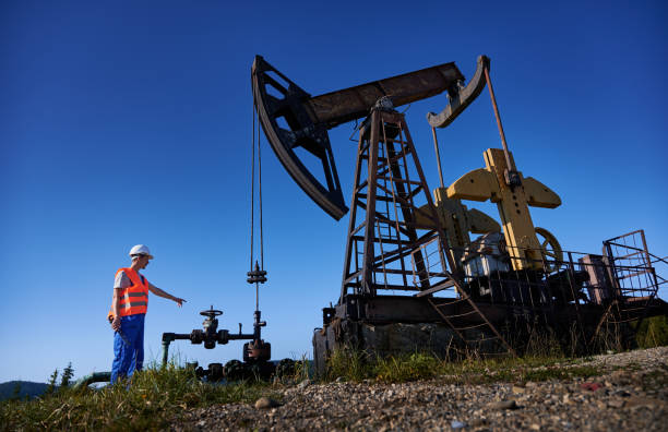 Oil man standing near petroleum pump jack under blue sky. stock photo