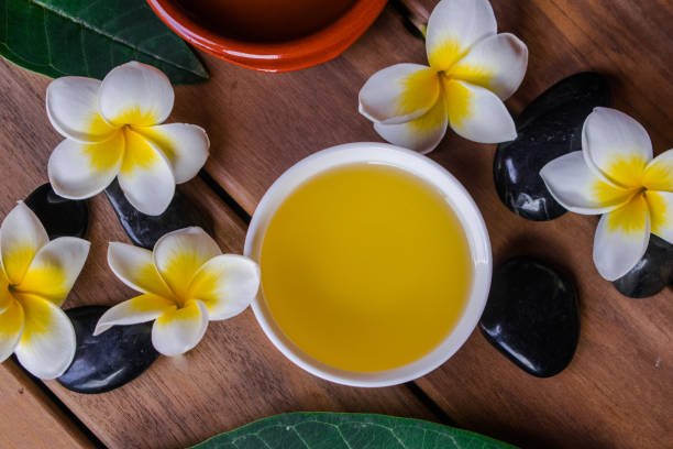 Oil massage therapy set Oil massage therapy set,with oil in a ceramic bowl, plumeria flowers and leaves, round black stones, on wooden surface petitgrain essential oil stock pictures, royalty-free photos & images