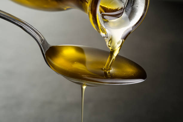 Oil pouring and dripping to the spoon Oil pouring and dripping to the spoon close up cooking oil stock pictures, royalty-free photos & images