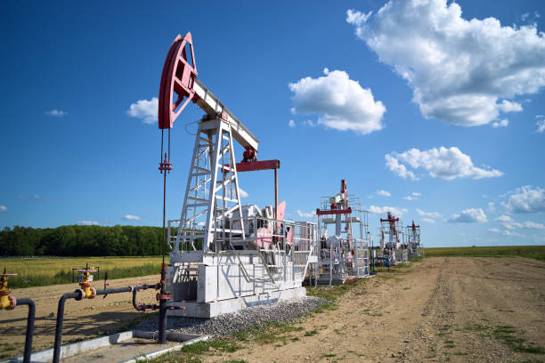 Oil pump, field, blue cloudy sky Oil pump, field, blue cloudy sky oil stock pictures, royalty-free photos & images