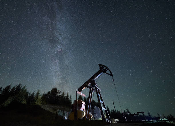 Oil pump jack at night time under starry sky. stock photo