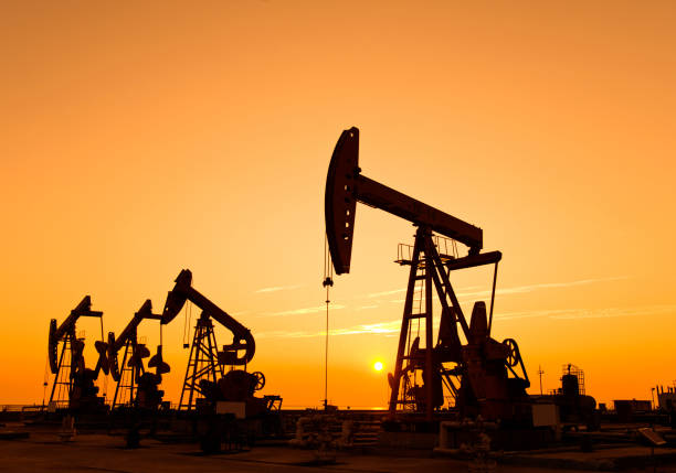 Oil pumps and rig at sunset Oil pumps and rig at sunset oil and gas stock pictures, royalty-free photos & images