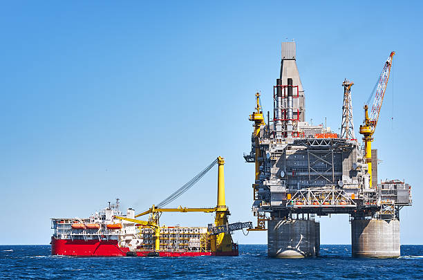 Oil rig Oil rig and support vessel on offshore area near Sakhalin island. Blue sky background oil industry stock pictures, royalty-free photos & images