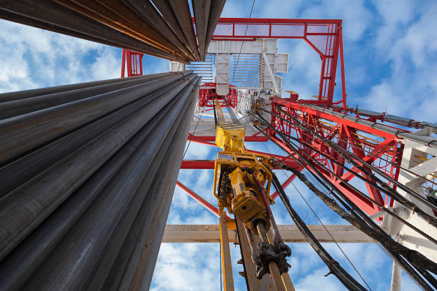 Oil rig with Pipes from bottom to top view Drilling rig view with Top Drive, many pipes, sky bottom up view in sunny weather in Siberia drill stock pictures, royalty-free photos & images