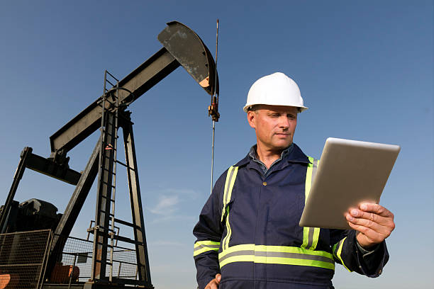 Oil Worker and Computer A royalty free image from the oil and gas industry of an oil worker using a tablet computer to surf the internet. oil and gas industry stock pictures, royalty-free photos & images