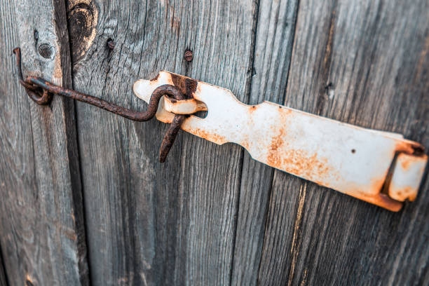Old and rusty hook locks the old dried up wooden barn door Rusty hook locks the old wooden doors of an abandoned barn rusty fence stock pictures, royalty-free photos & images