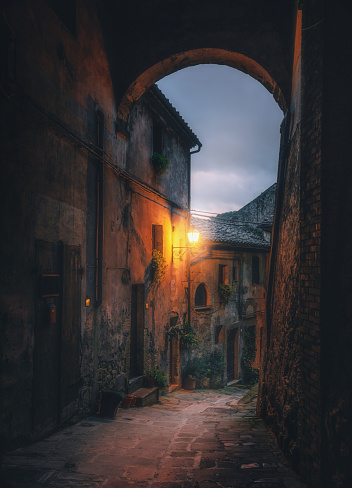 Old arched cobblestone street with street light at night in medieval town Sorano, Tuscany, Italy