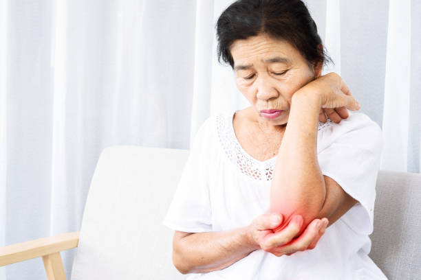 old Asian woman suffering from tennis elbow pain hand holding her ache arm stock photo