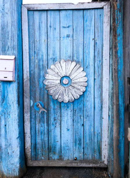 Old blue door in Russian village style with white flower in center stock photo