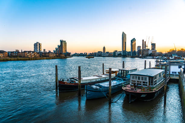 старые лодки у реки темзы, с современными зданиями в челси лондон - fulham стоковые фото и изображения
