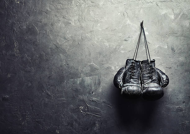 old boxing gloves nailed to the textured wall old boxing gloves hang on nail on texture wall with copy space for text. Retirement concept boxing gloves stock pictures, royalty-free photos & images