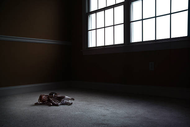 Old Doll Sitting in Empty, Dark Room stock photo