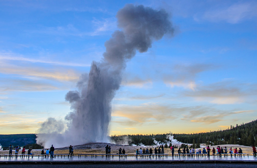 Groups of people have been waiting to watch, experience and photograph this Old Faithful  eruption just after sunset on a sunny early autumn day.