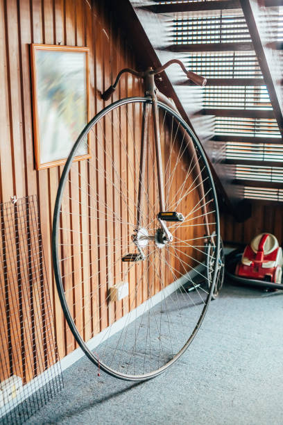 Old fashioned bicycle with one big and one small wheel under the stairs in a house stock photo