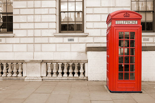 Old fashioned UK red telephone box on Whitehall, London Traditional old style UK red phone box isolated against a sepia tinted background. red telephone box stock pictures, royalty-free photos & images